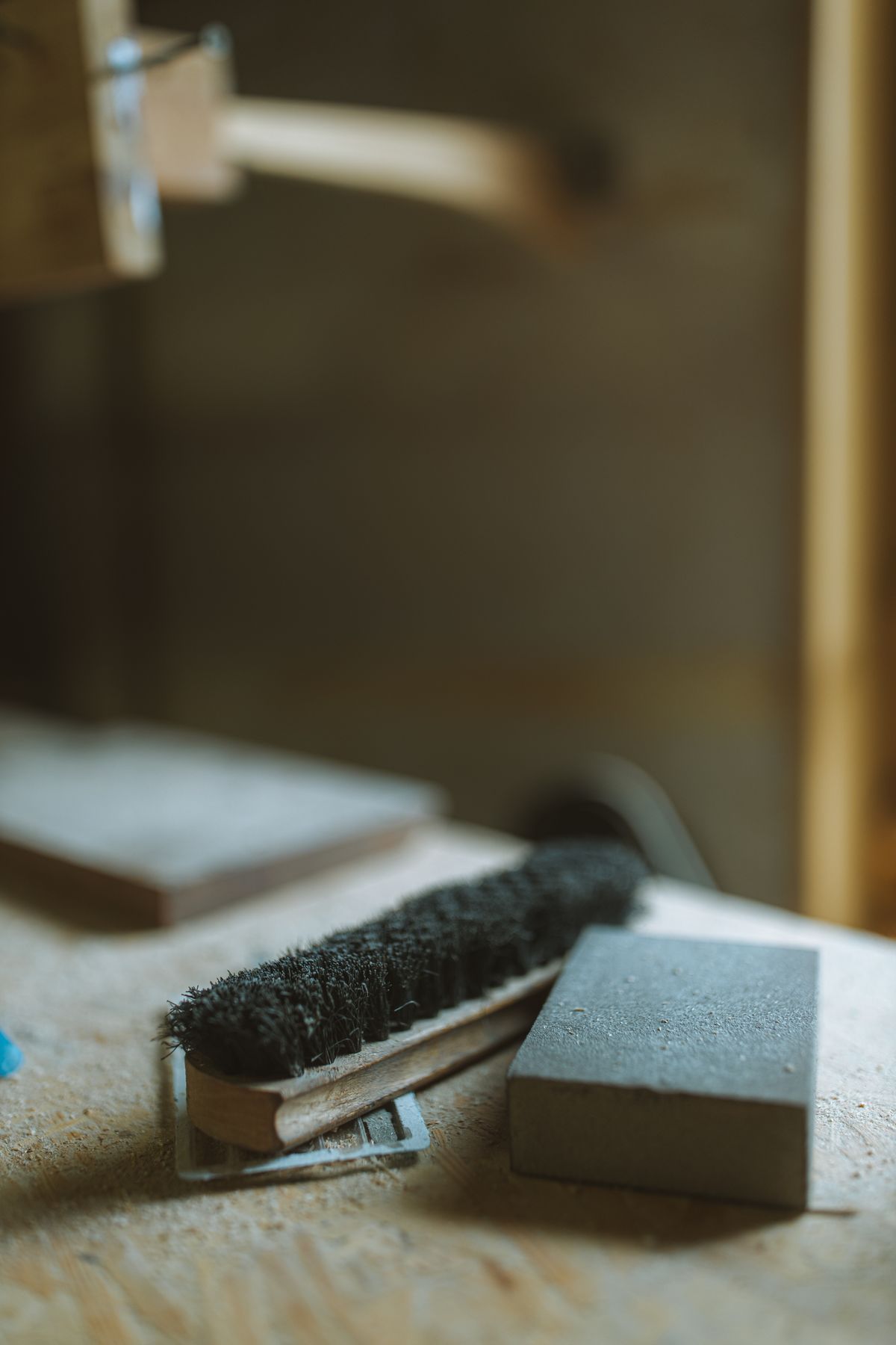 A bench brush resting on a wooden work surface