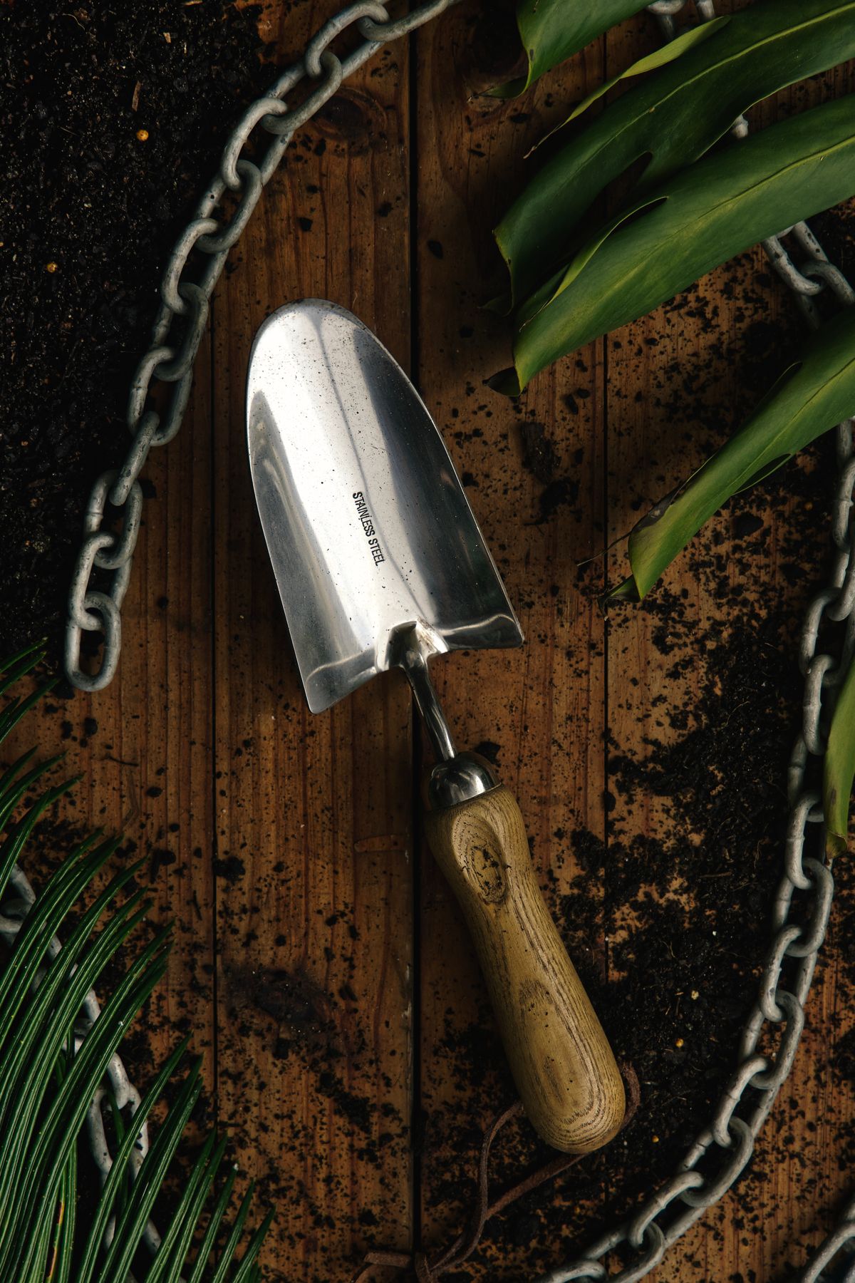 Garden hand trowel on wood beside soil and leaves