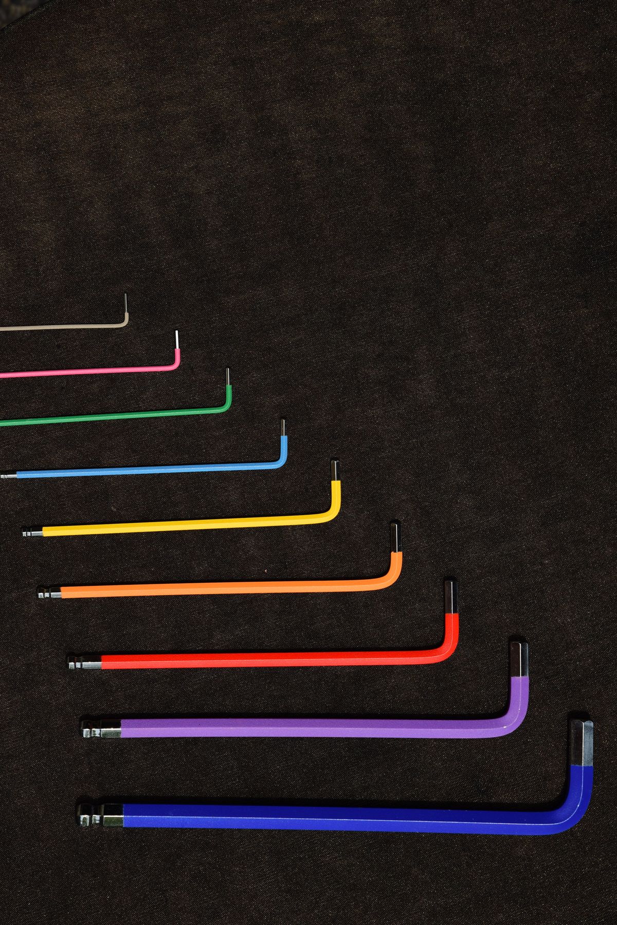 A set of coloured hex keys arranged on a dark surface
