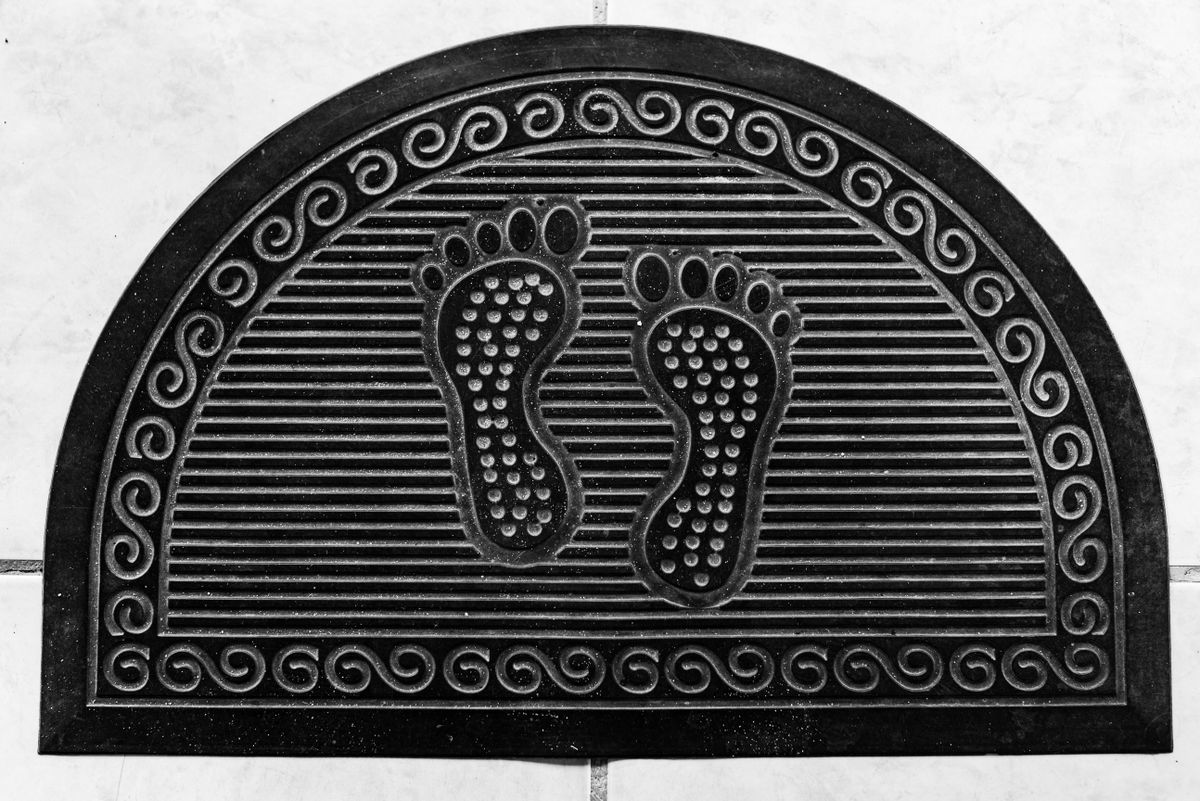 Rubber door mat with textured drainage surface