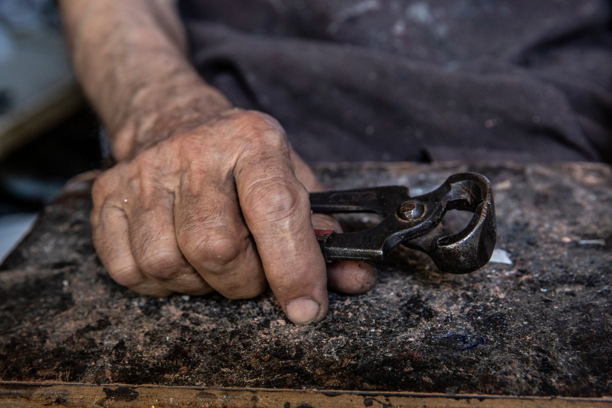 A hand holding pliers over a workbench